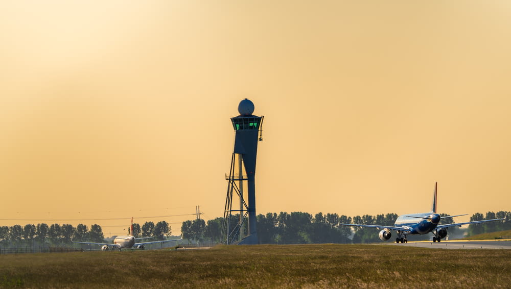 a plane on a runway with a tower in the background
