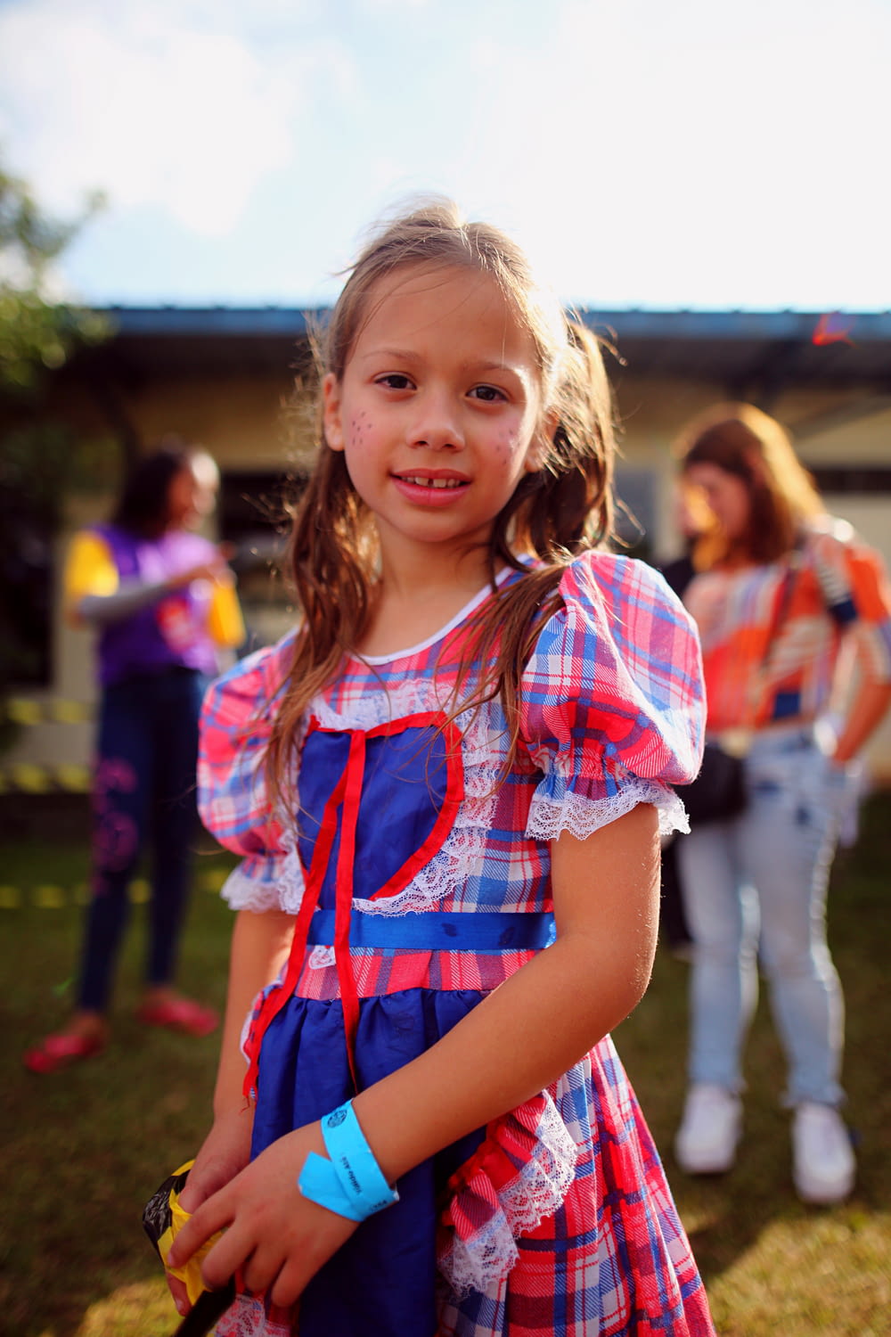 a little girl in a plaid dress holding a cell phone