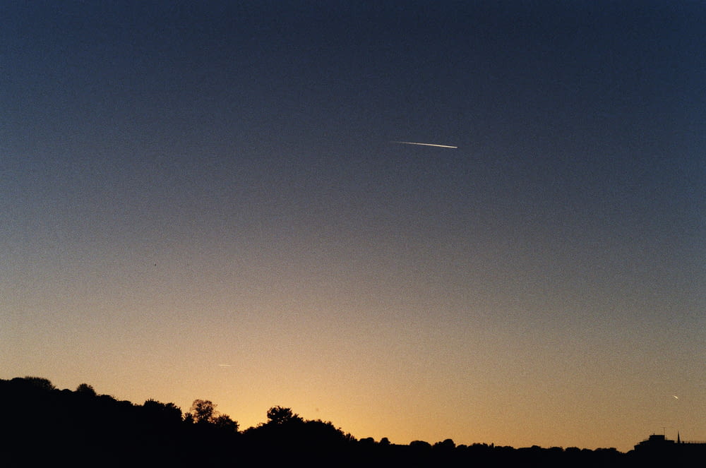 a plane is flying in the sky at sunset