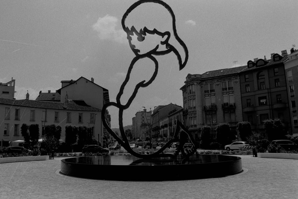 a black and white photo of a statue in a square