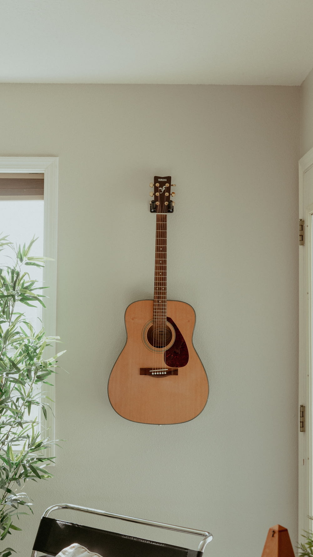 a guitar hanging on a wall next to a potted plant
