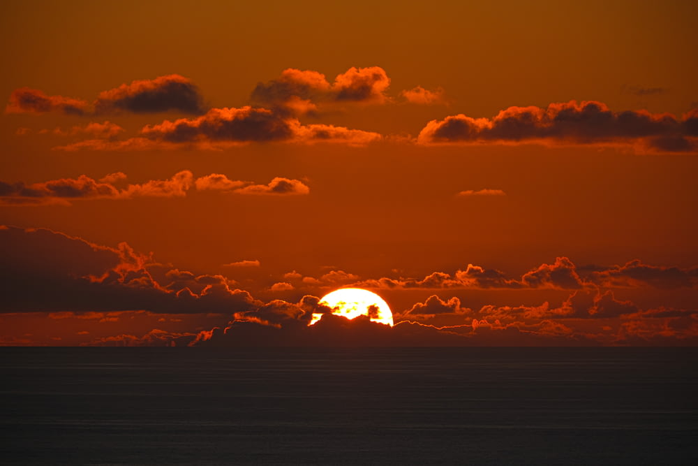 Il sole sta tramontando sull'oceano con le nuvole