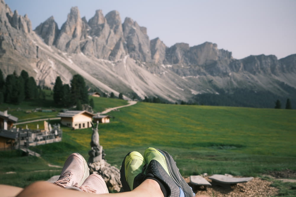 a pair of feet resting on a rock in front of a mountain range