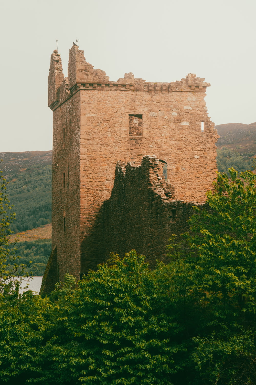 an old stone castle surrounded by trees and hills