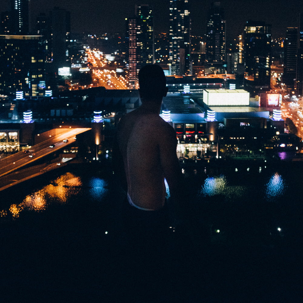 a man standing in front of a city skyline at night
