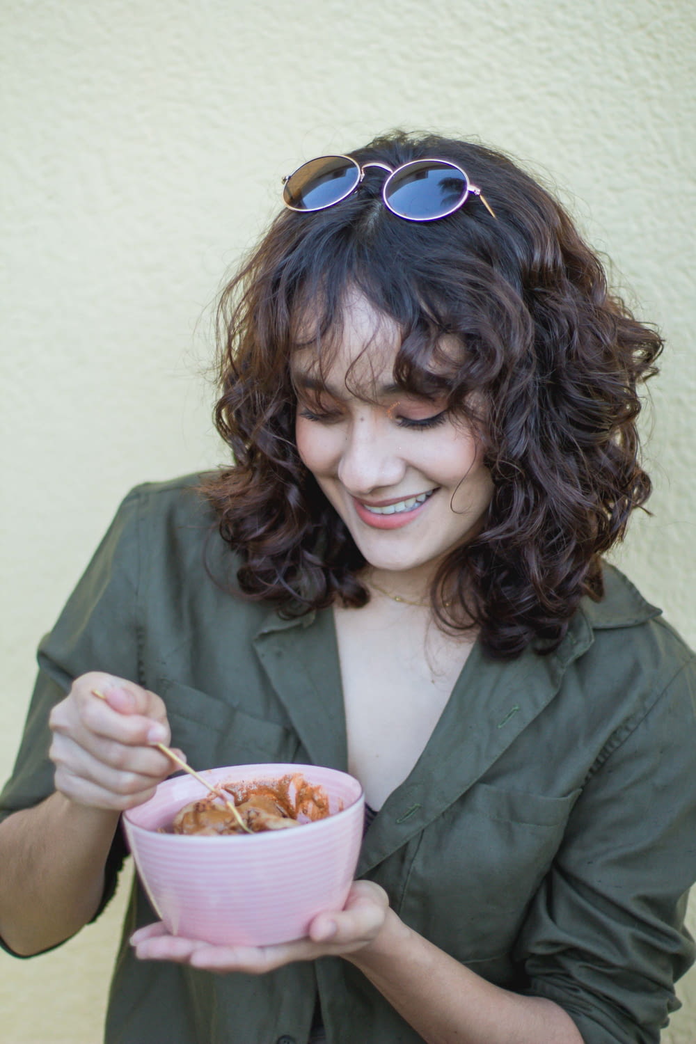 a woman in a green shirt is holding a bowl of food
