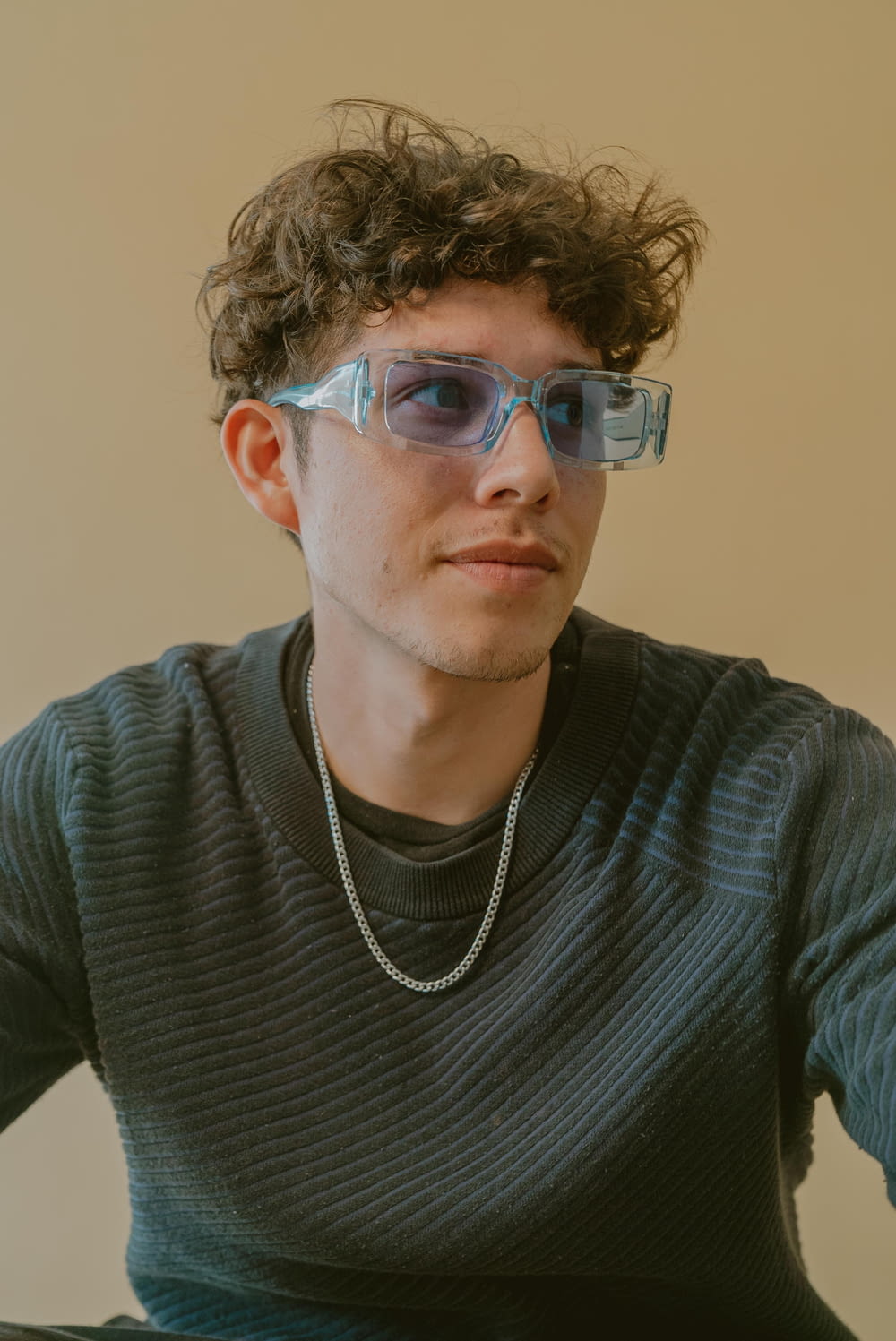 a young man wearing glasses and a necklace