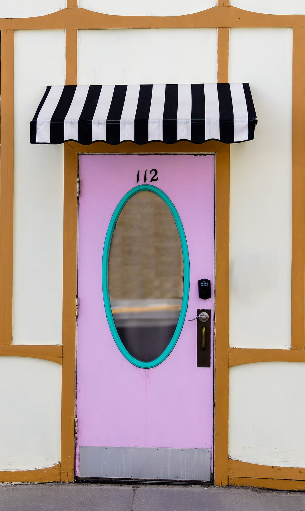 a pink door with a black and white awning