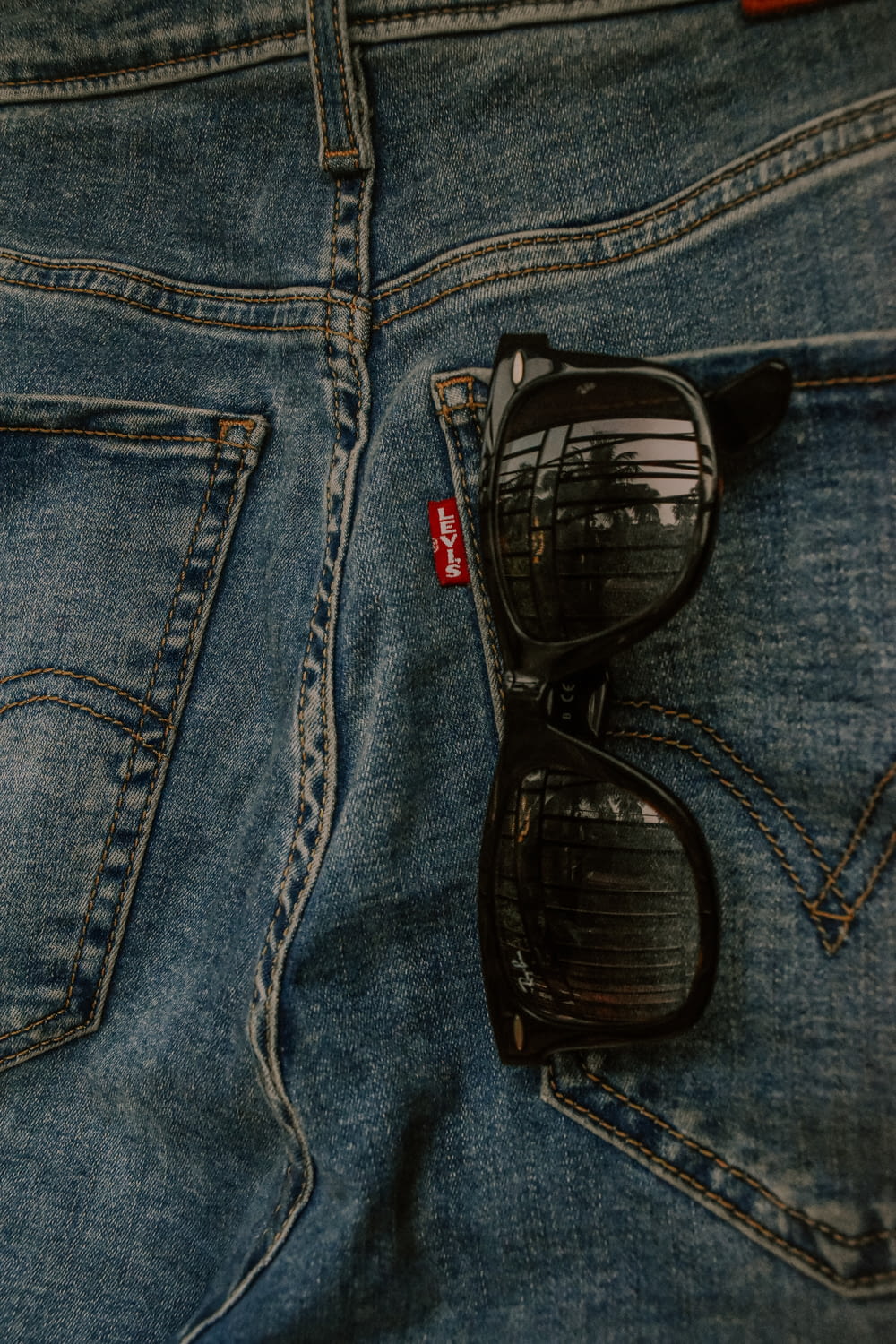 a pair of sunglasses sitting on the back of a pair of jeans