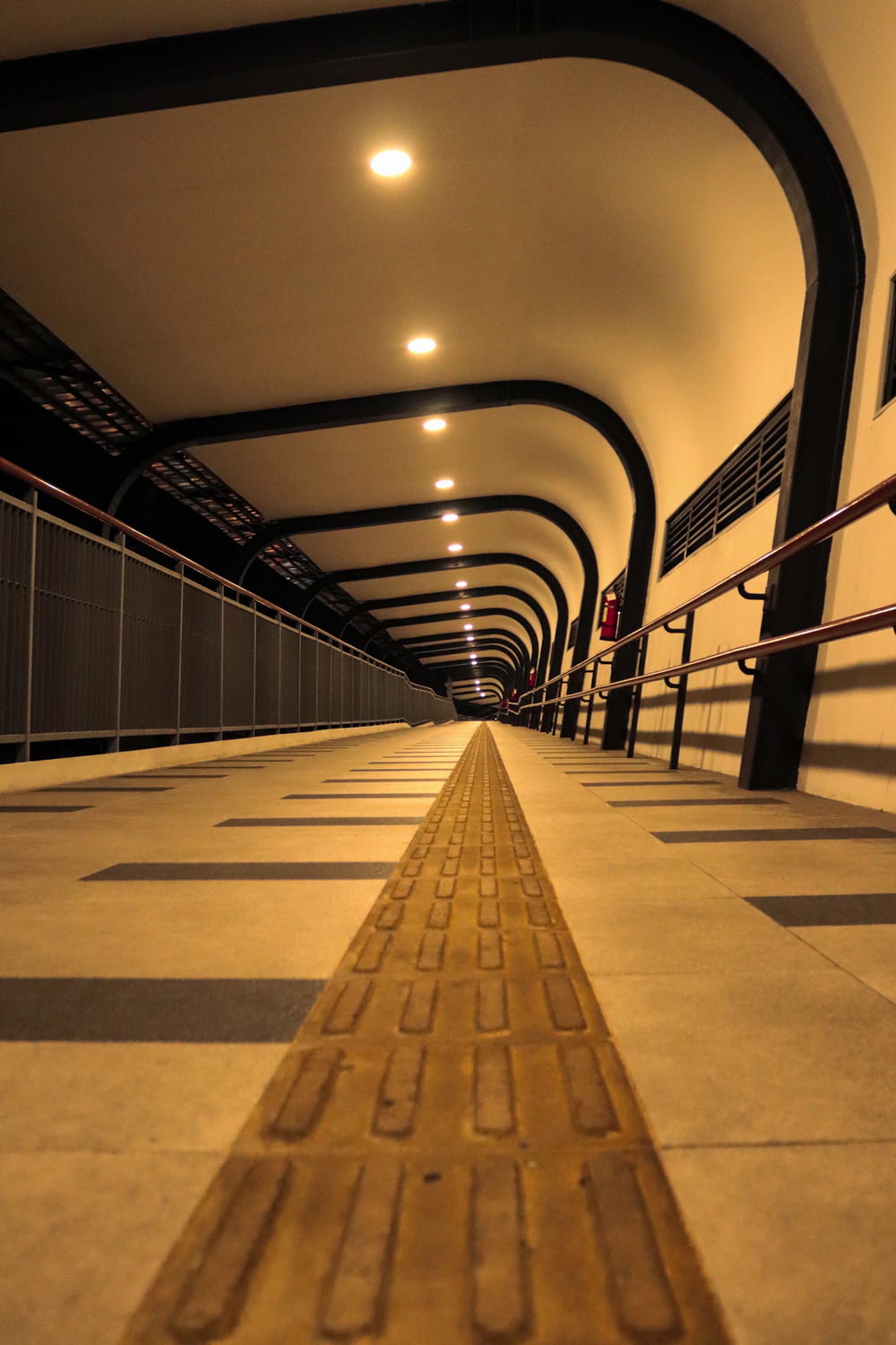 a long walkway in a tunnel with a metal railing
