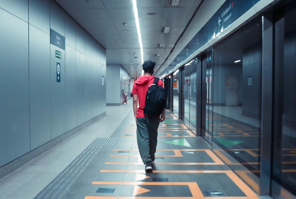 a man with a backpack walks down a hallway