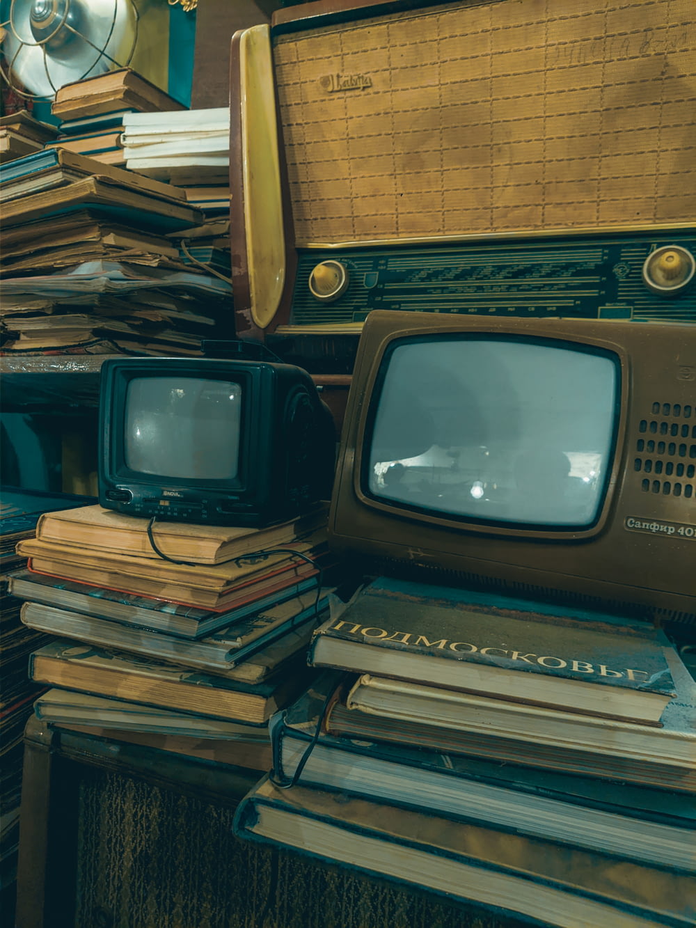 a pile of books and a tv sitting on top of a table