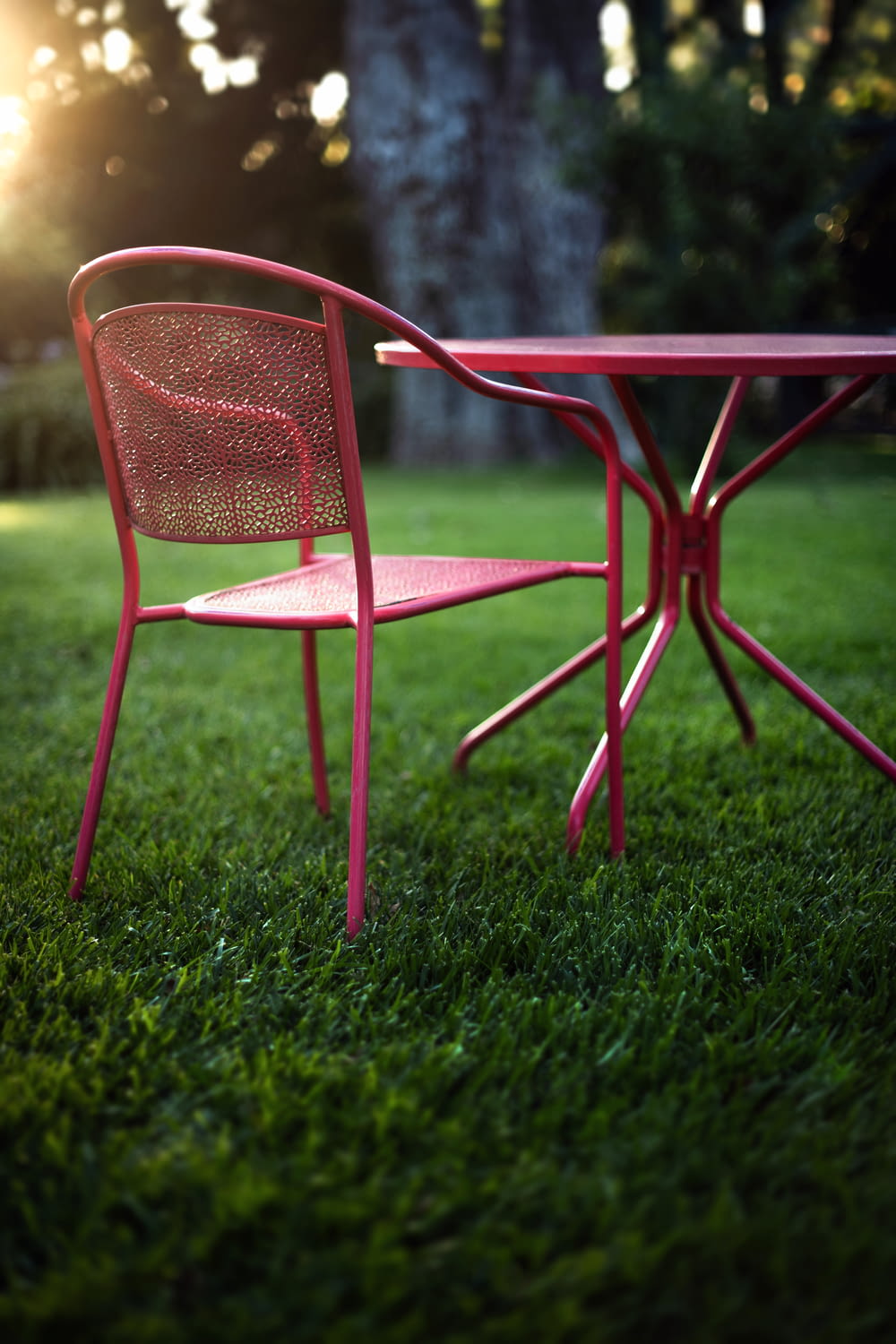 a red table and chair sitting on top of a lush green field