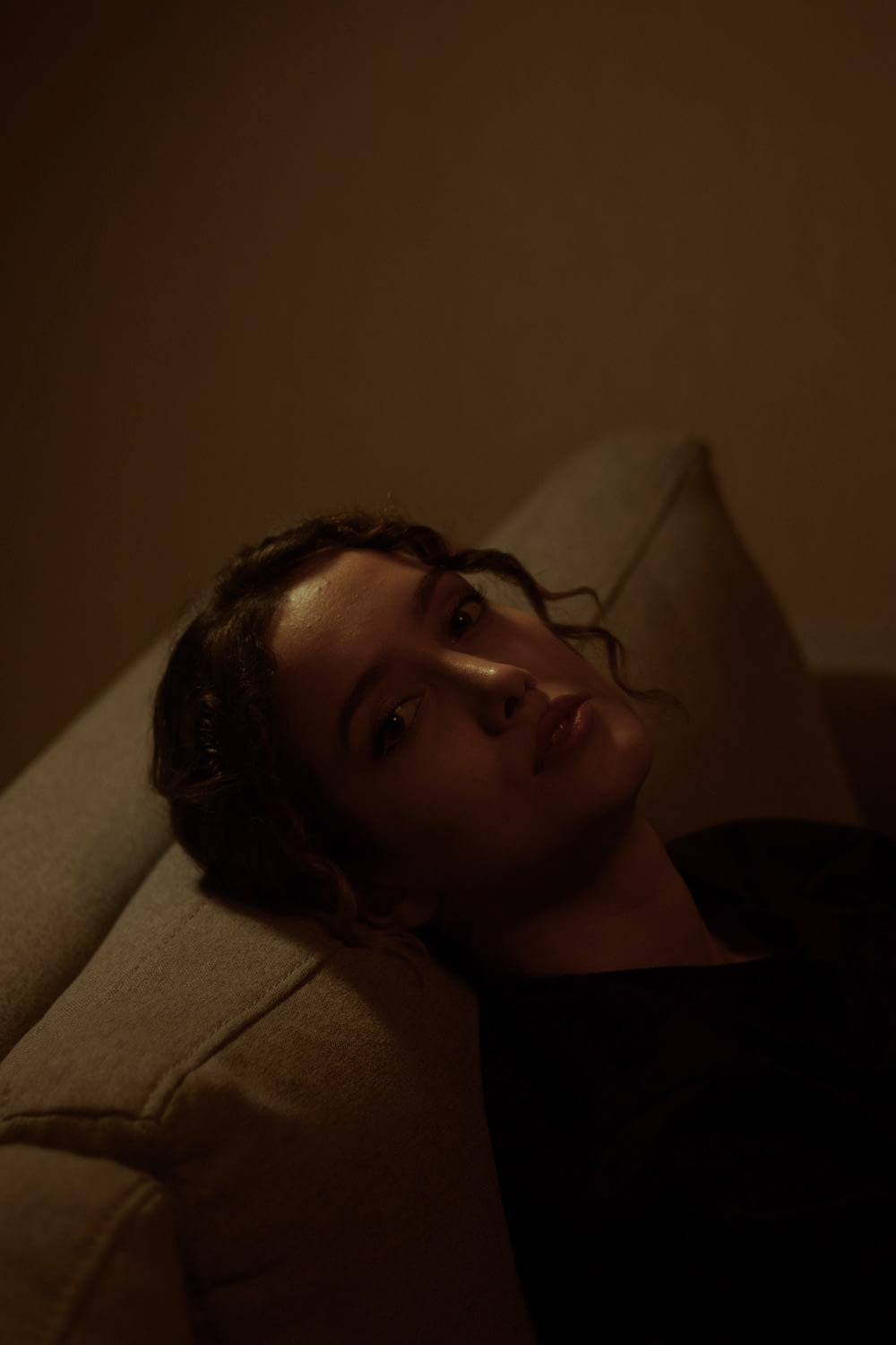 a woman laying on a couch in a dark room