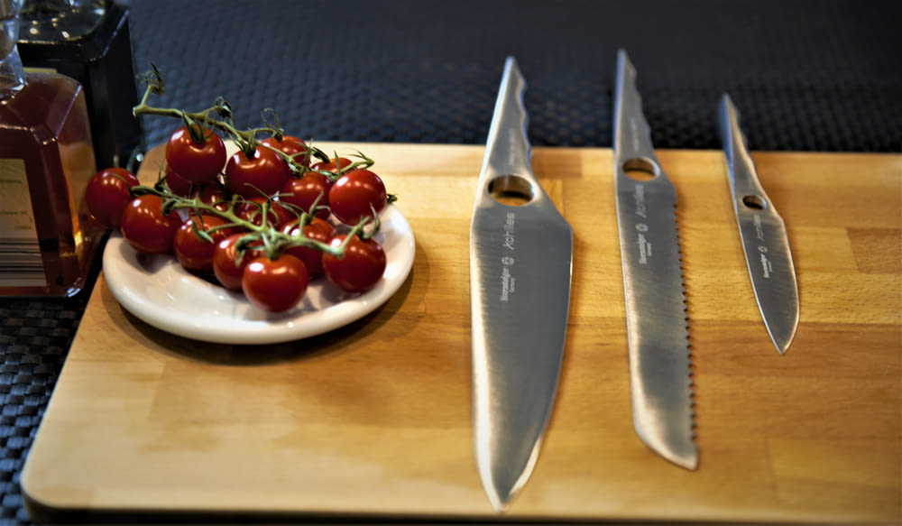 a plate of tomatoes and a knife on a cutting board