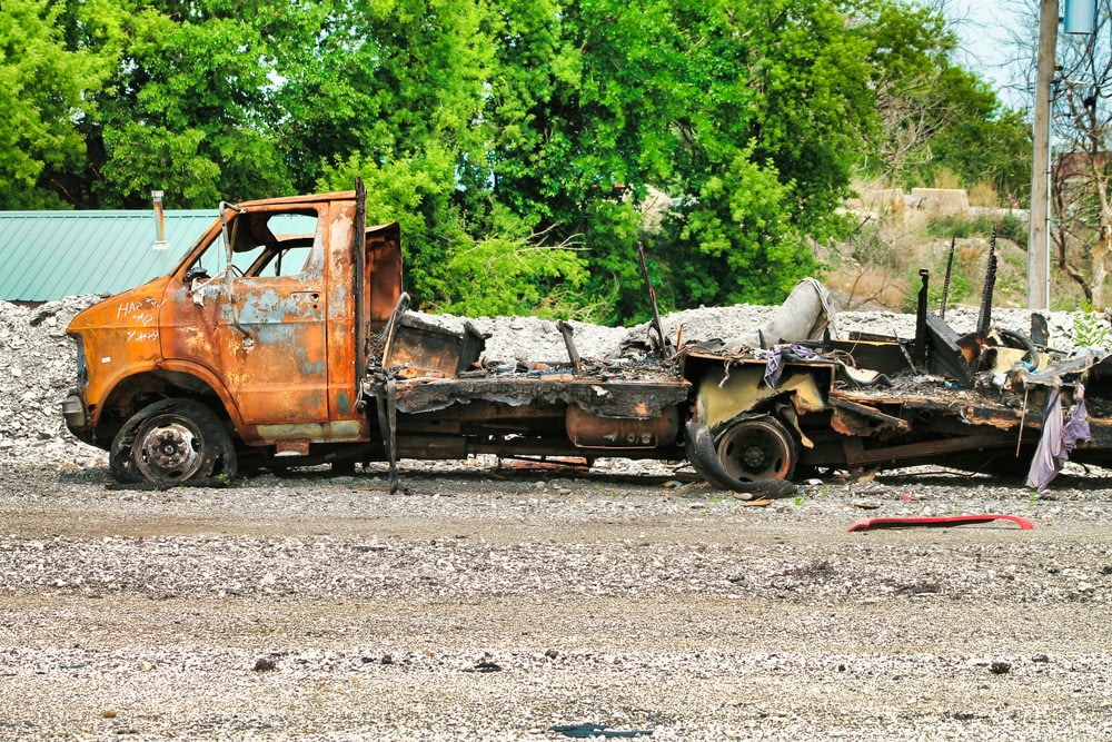 a rusted out truck sitting on top of a dirt field