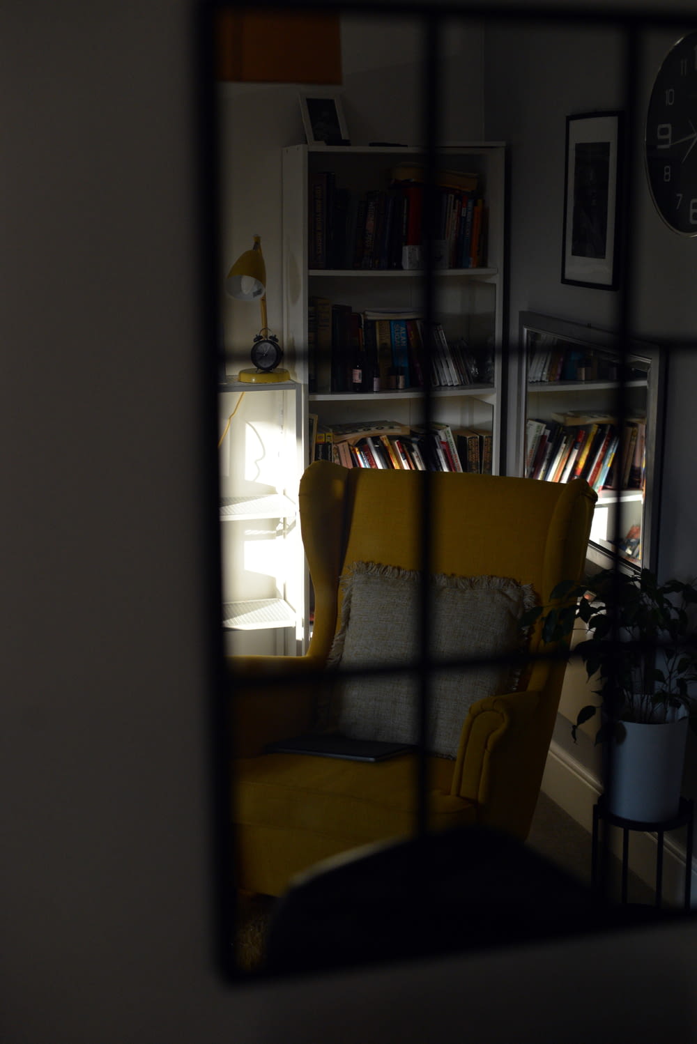 a yellow chair sitting in a living room next to a book shelf