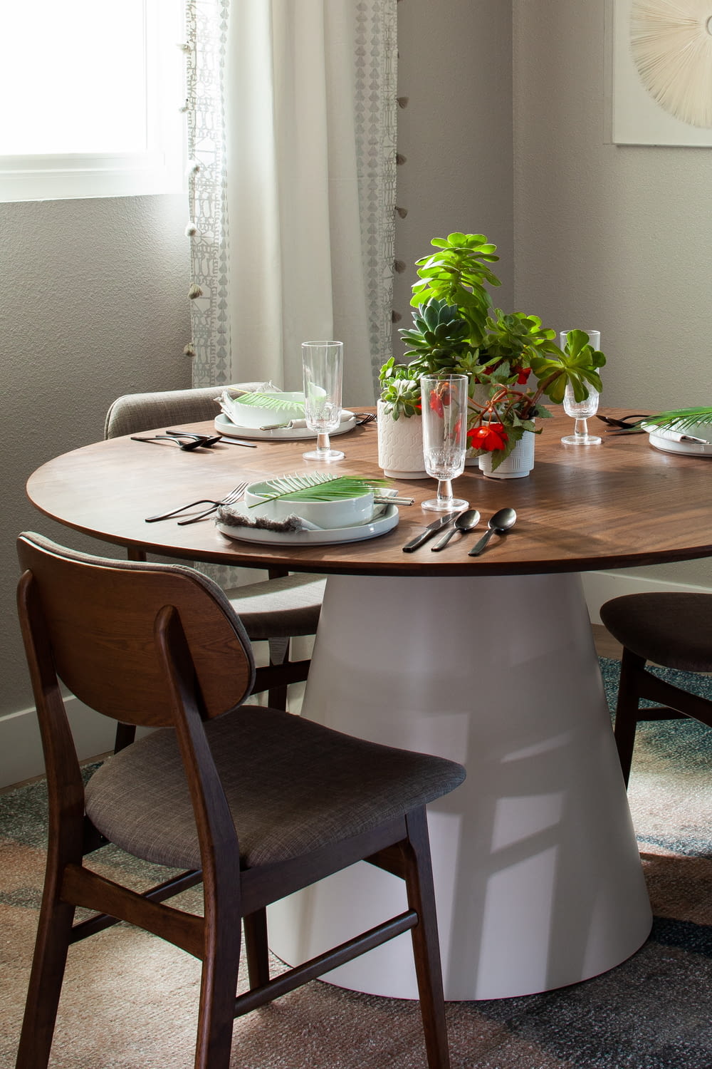 a dining room table with chairs and a potted plant