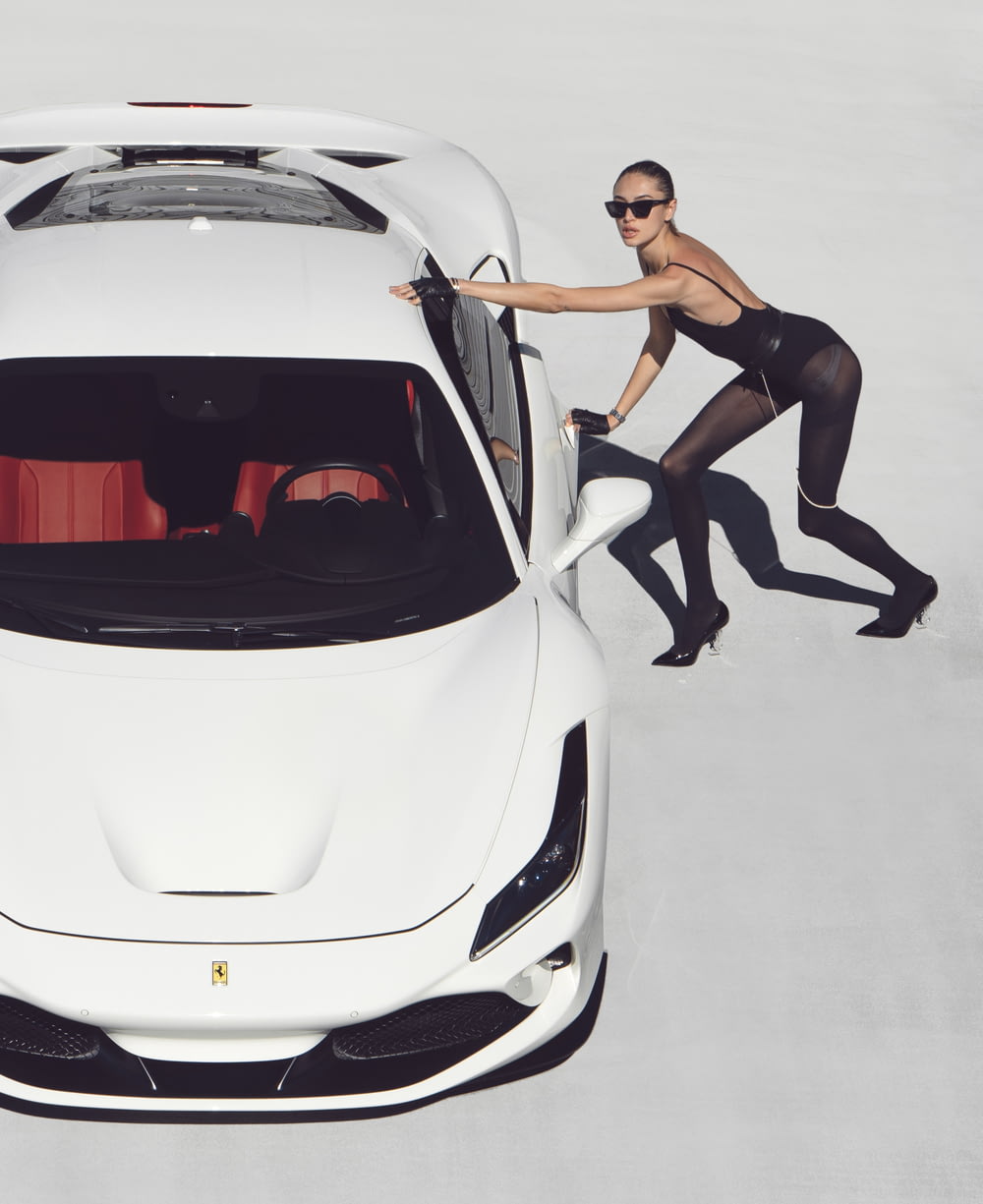 a woman standing next to a white sports car