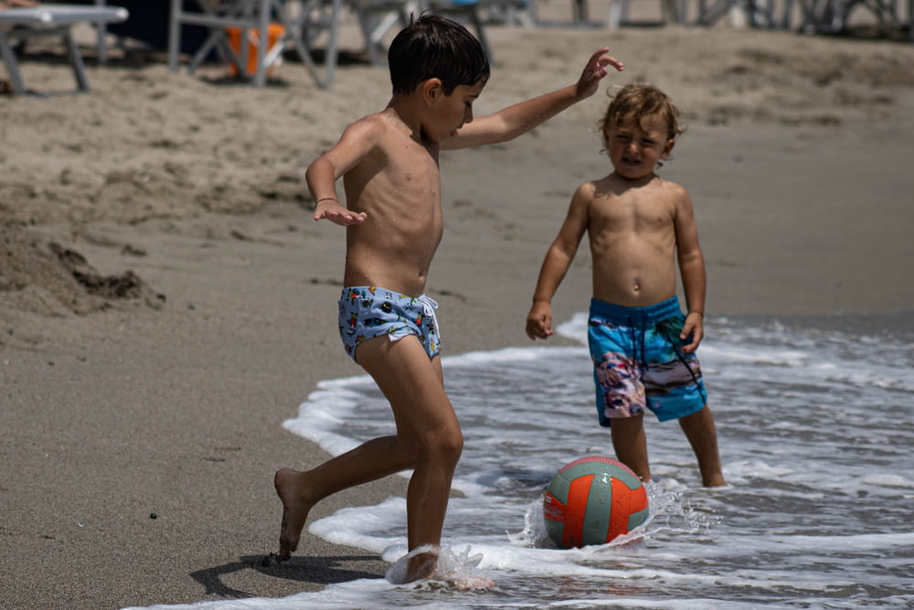 Dos niños jugando con una pelota en la playa