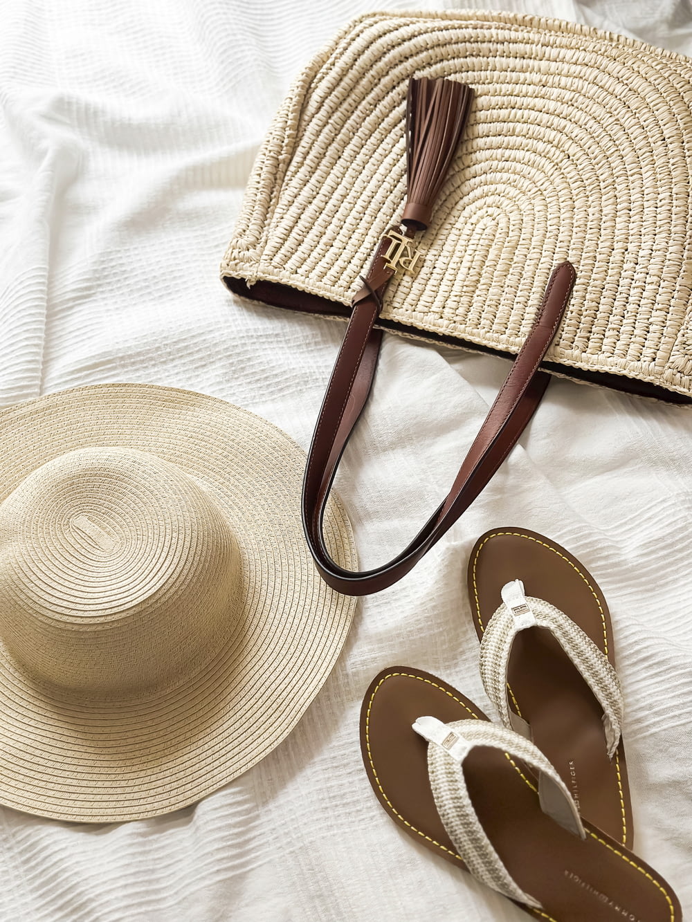 a hat, sandals, and a purse on a bed