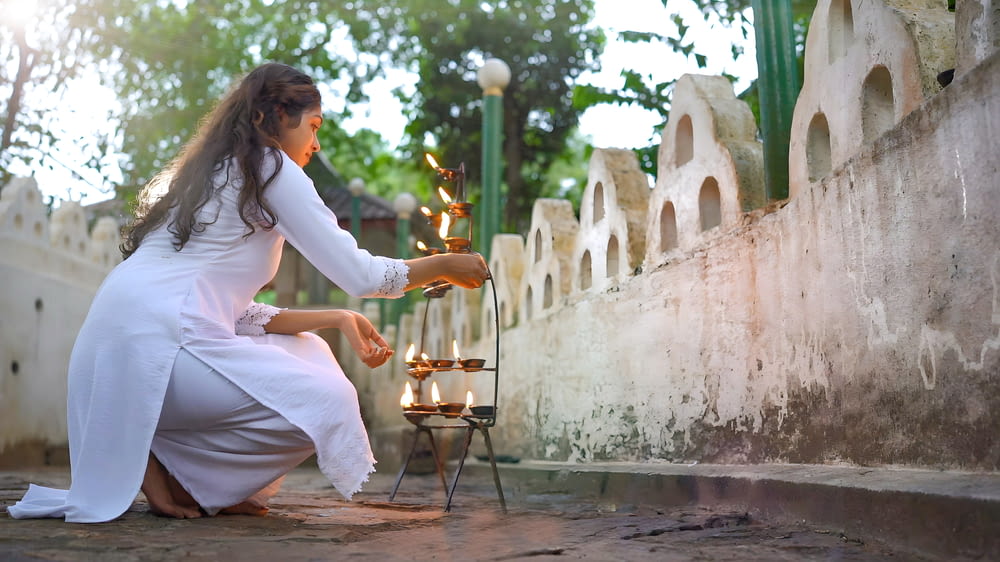 a woman in a white dress lighting candles