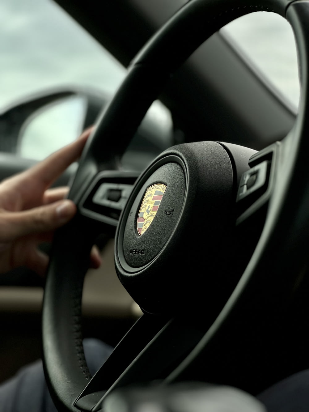 a steering wheel of a car with a woman's hand on the steering wheel