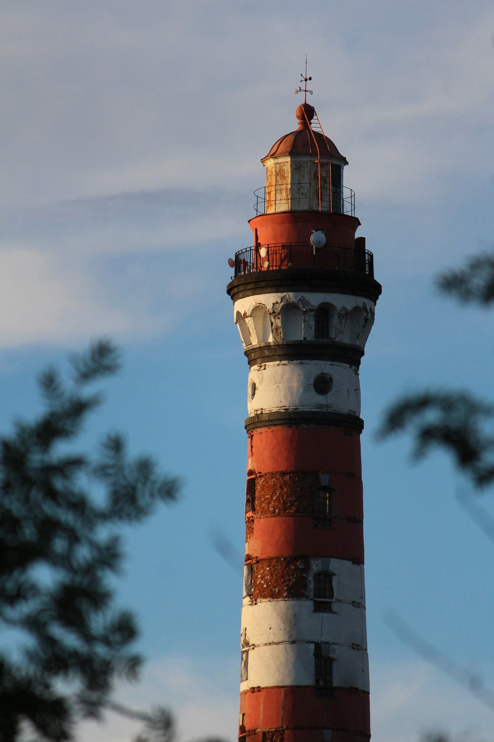 a red and white lighthouse with trees in the background