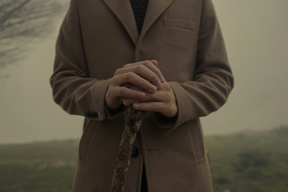 a man in a coat and tie holding a stick