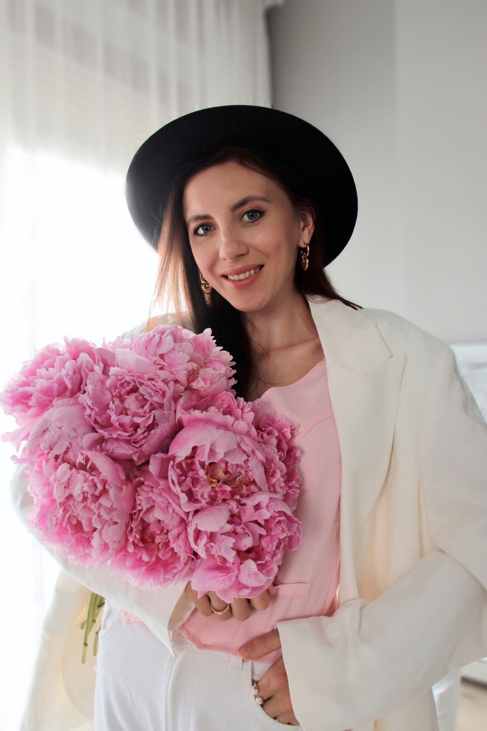 Une femme coiffée d’un chapeau tenant un bouquet de fleurs