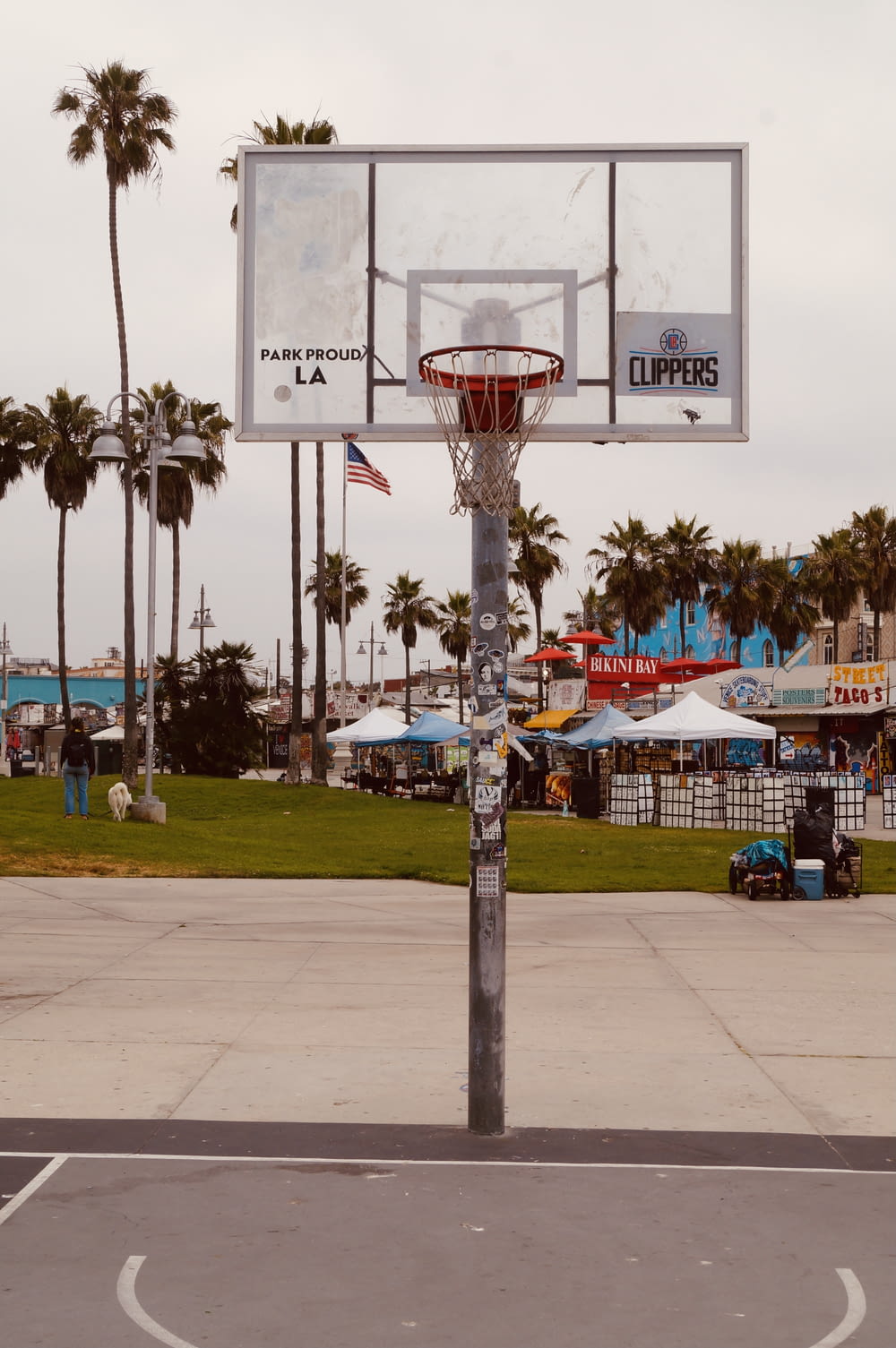 a basketball hoop in a parking lot with palm trees in the background