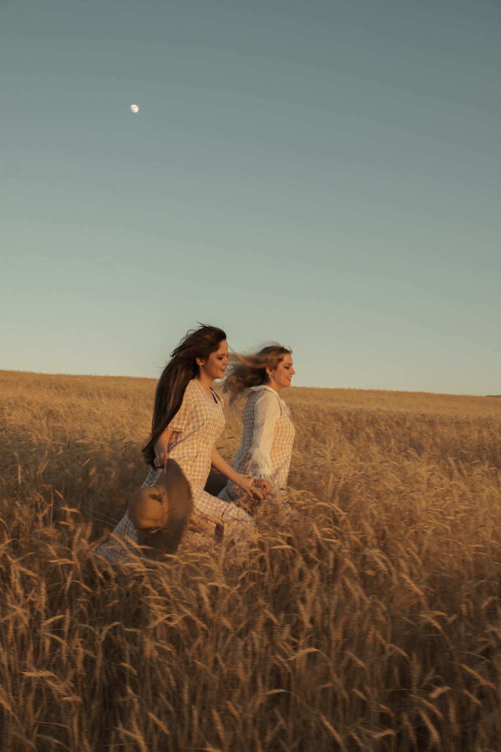 two women walking through a field of tall grass