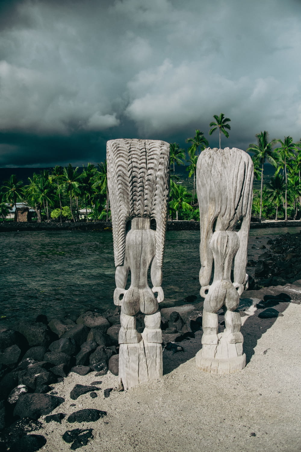 a couple of statues sitting on top of a sandy beach