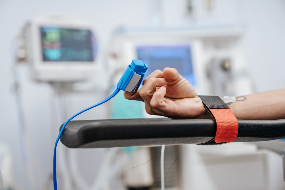 a hand on a hospital bed holding a device