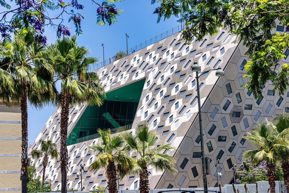 a building with a triangular design and palm trees in front of it