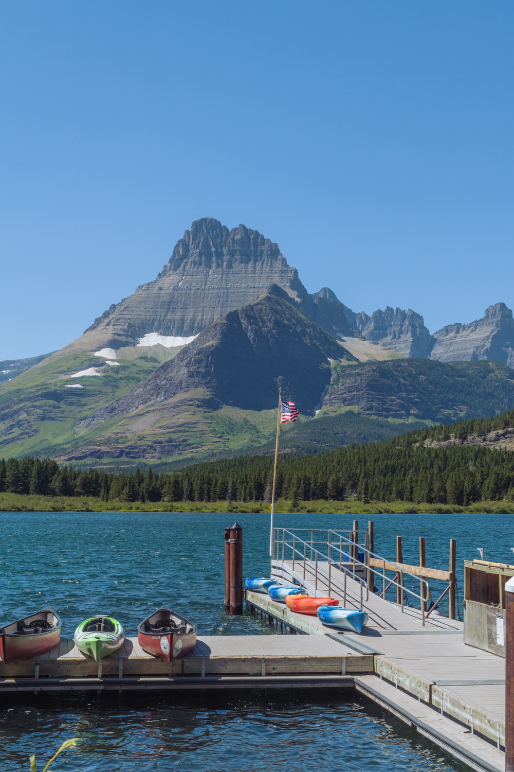 a dock with kayaks on a lake with mountains in the background