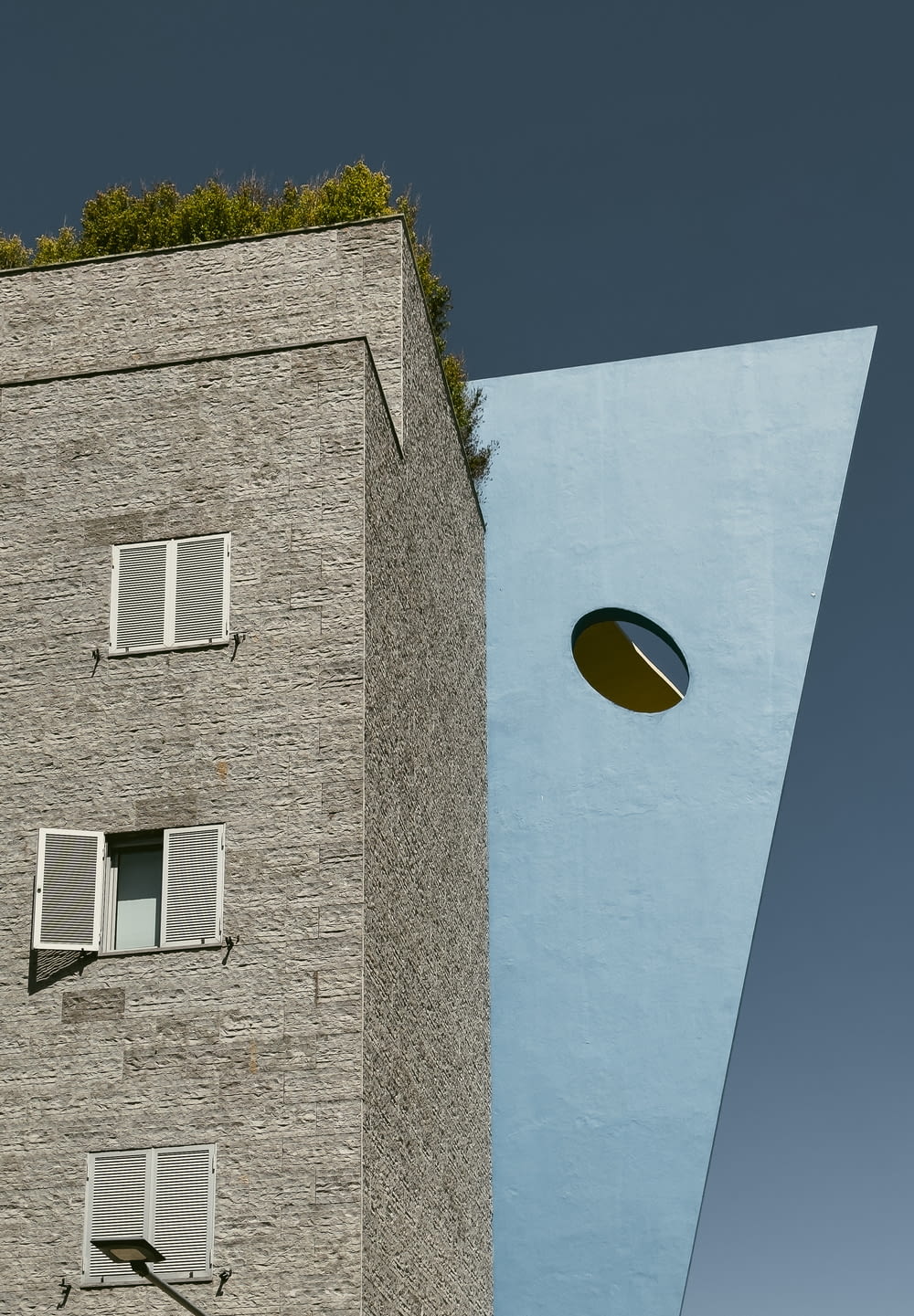 a tall blue building with a round window