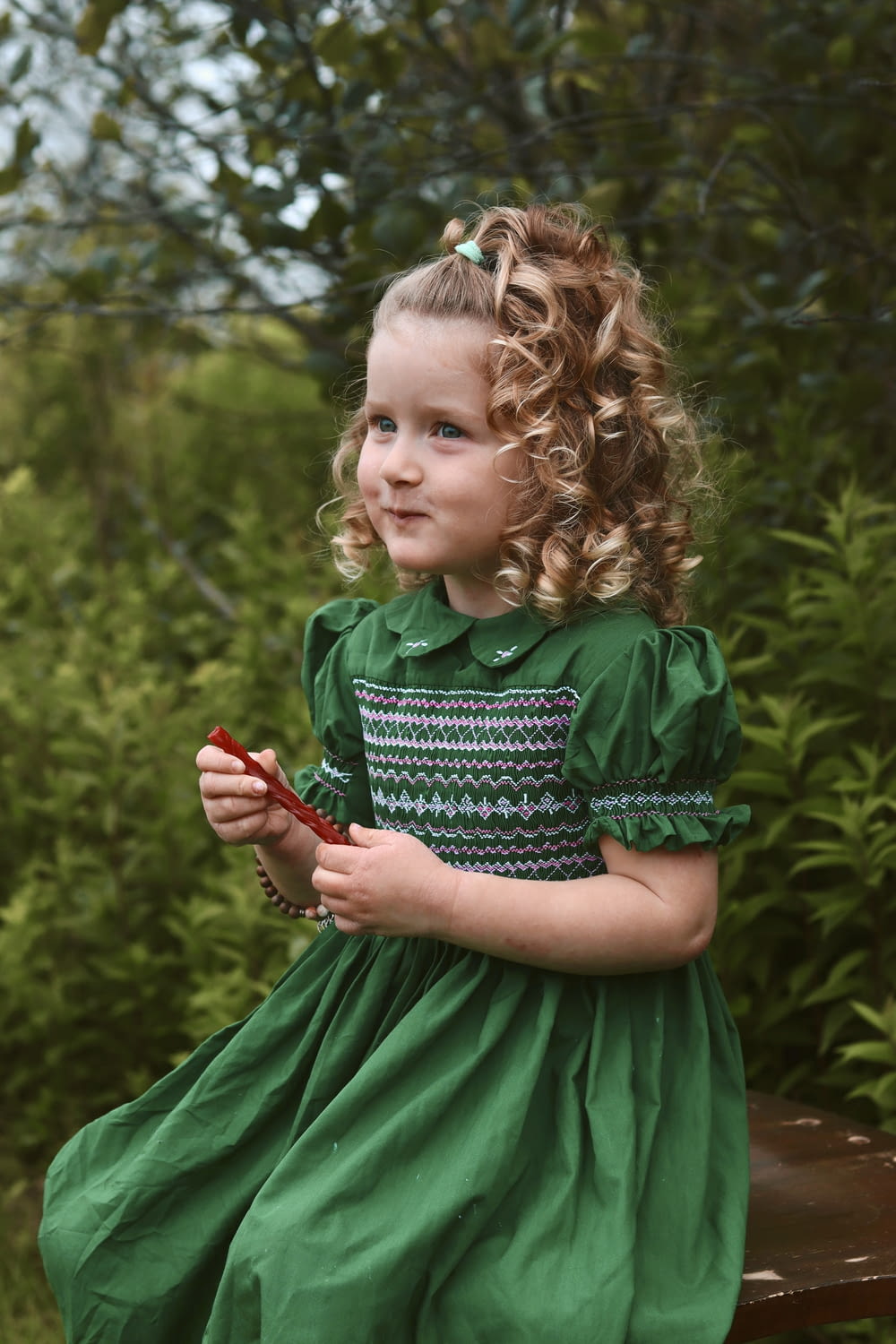 Une petite fille en robe verte assise sur un banc
