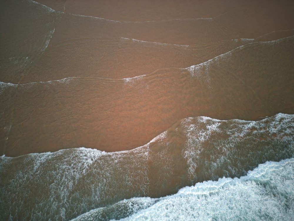 an aerial view of a beach with waves coming in