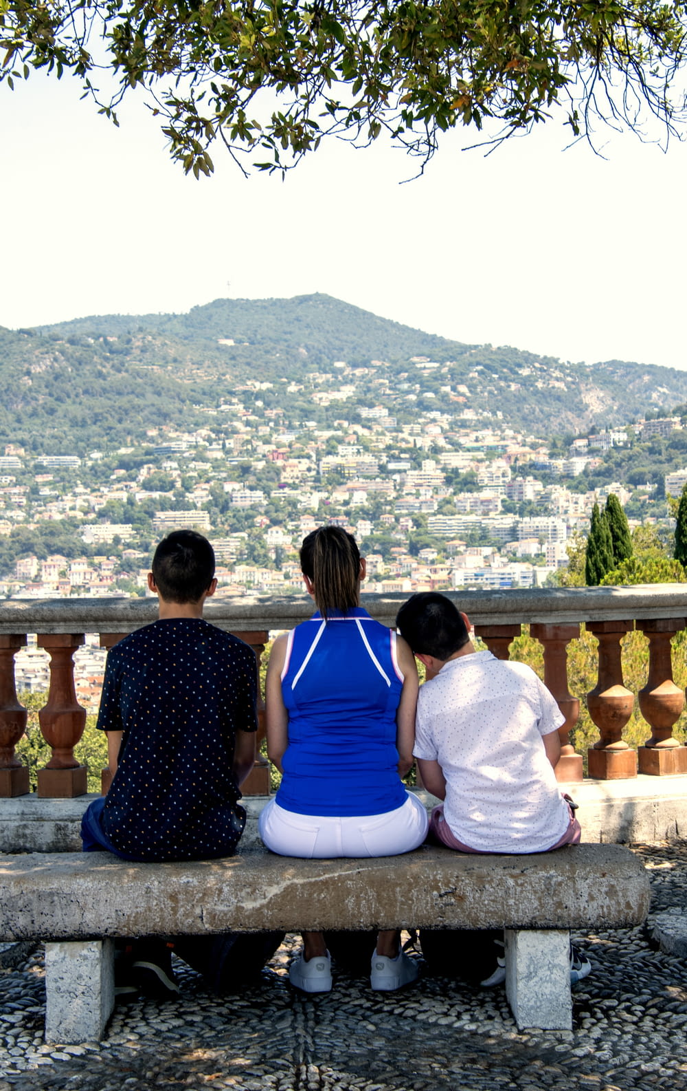 three people sitting on a bench overlooking a city