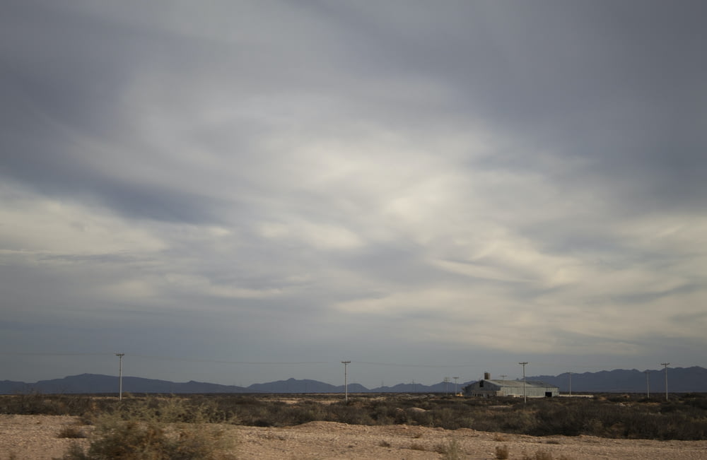 a cloudy sky over a desert landscape with mountains in the background