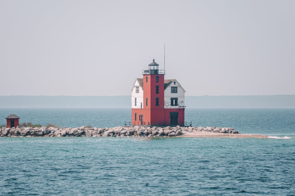 a red and white lighthouse sitting on top of a small island