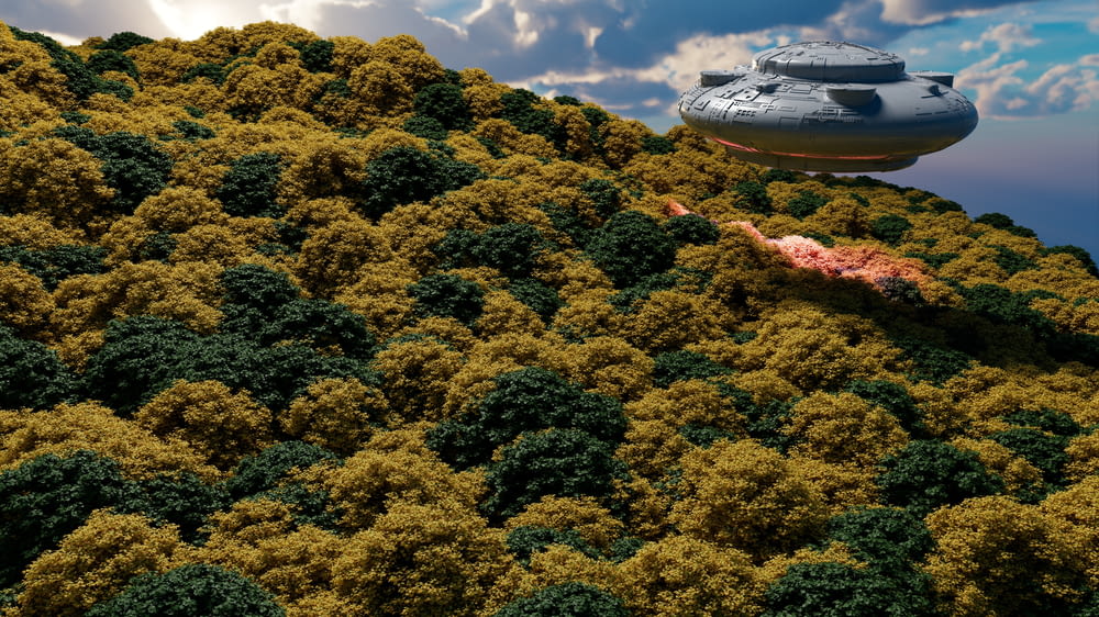 a large object flying over a lush green hillside