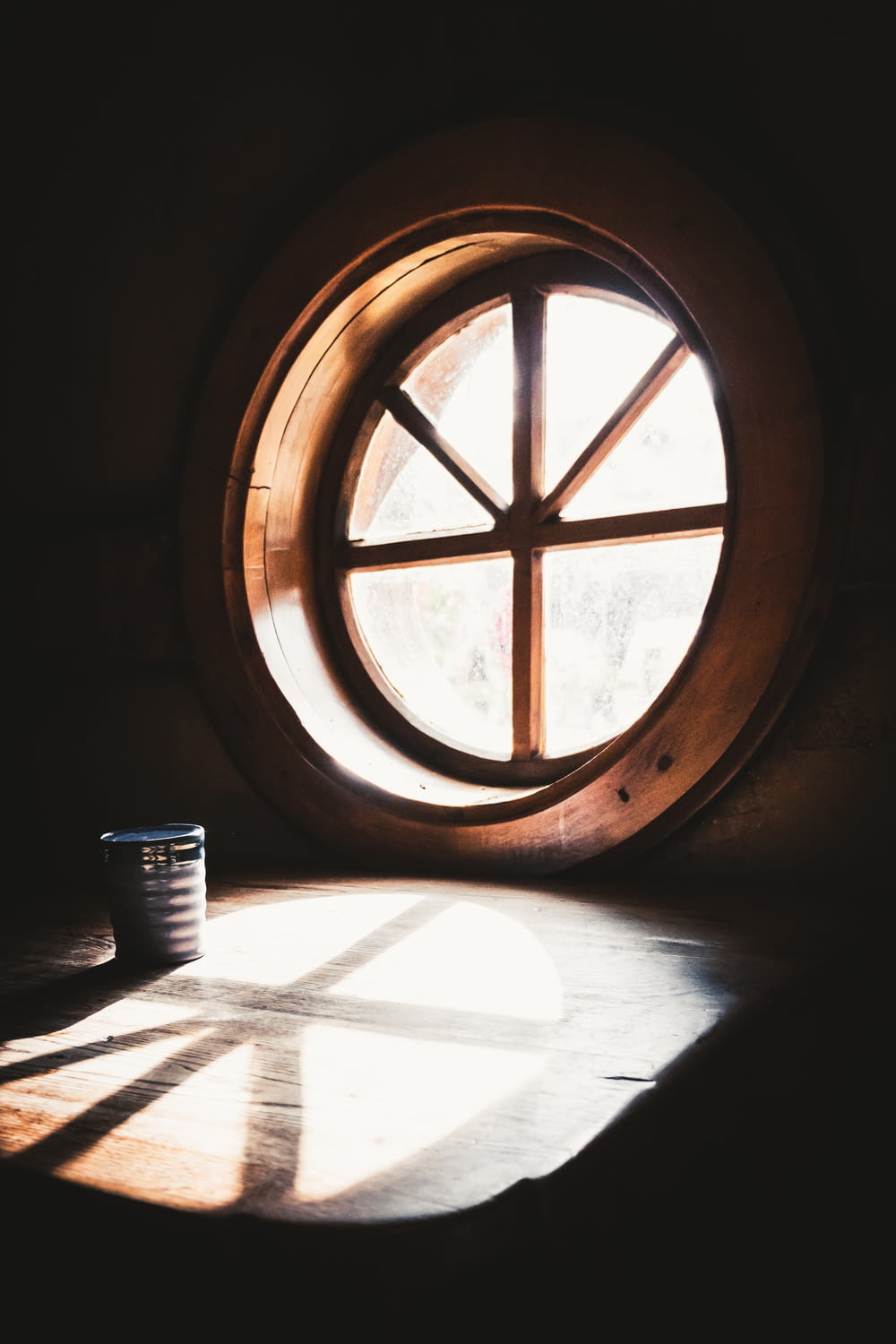 a round window with a wooden frame in a dark room