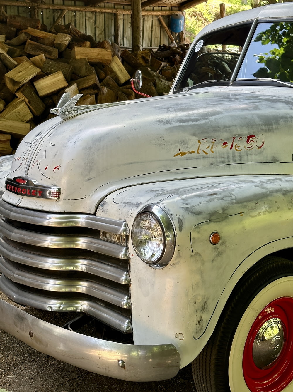 an old truck parked next to a pile of wood