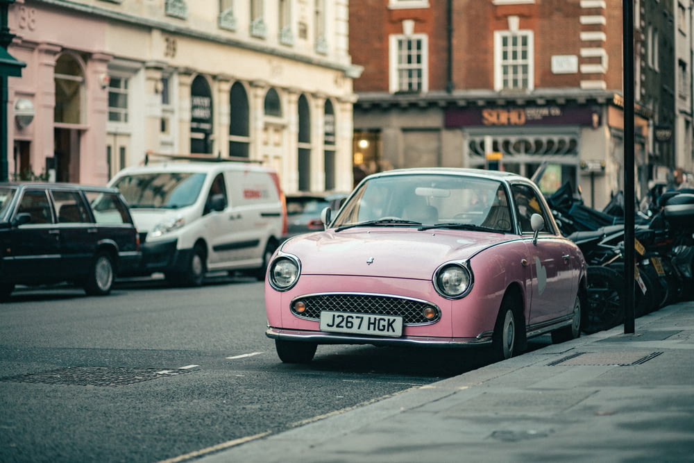un'auto rosa parcheggiata sul ciglio della strada