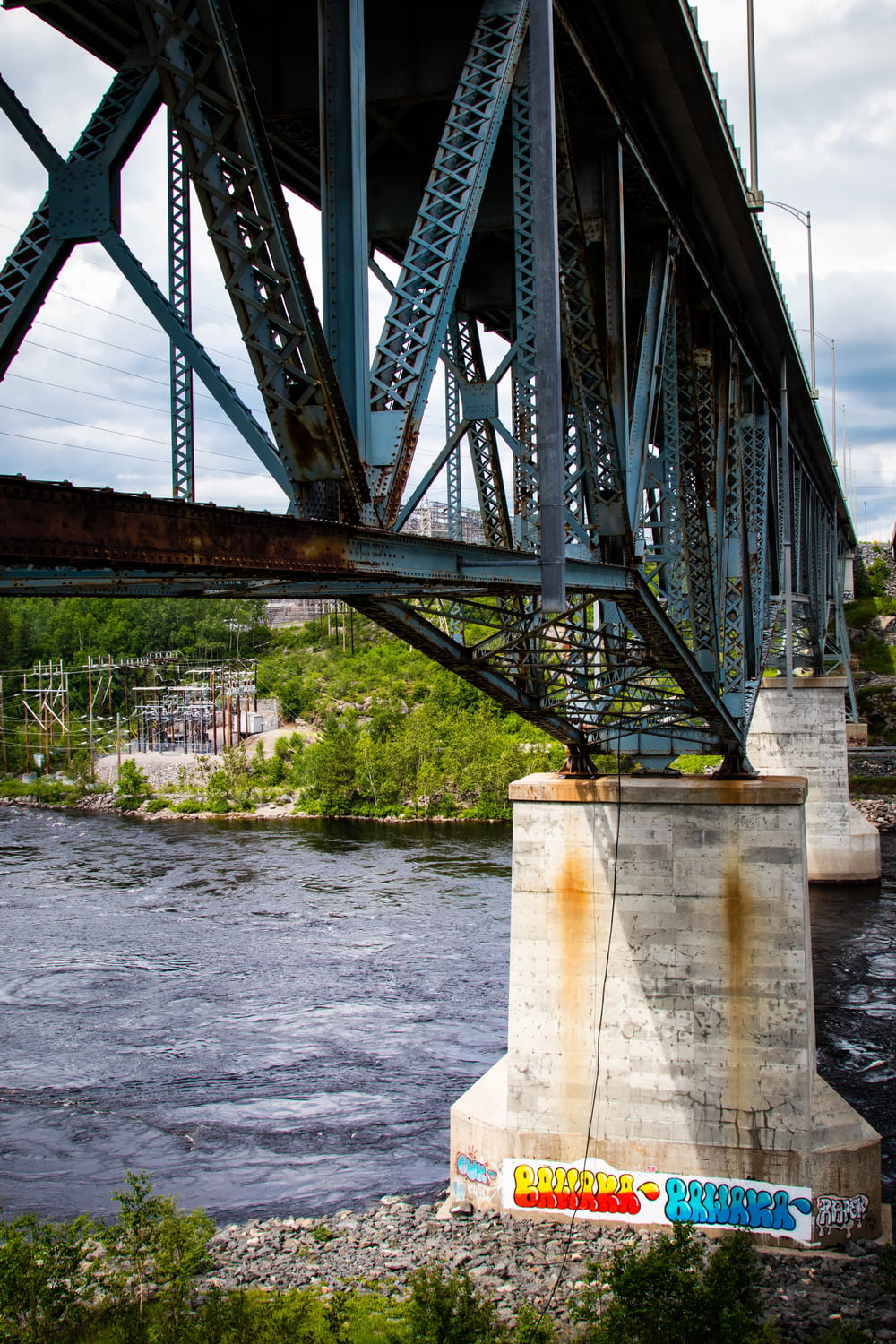 a bridge over a river with graffiti on it