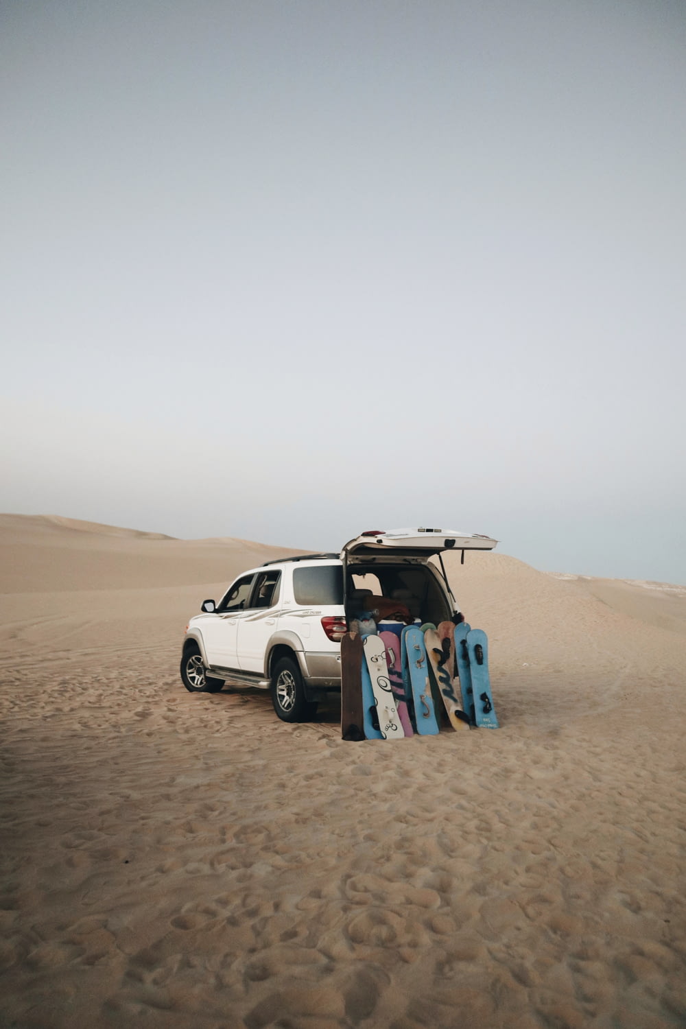 a car with a surfboard on top of it in the sand