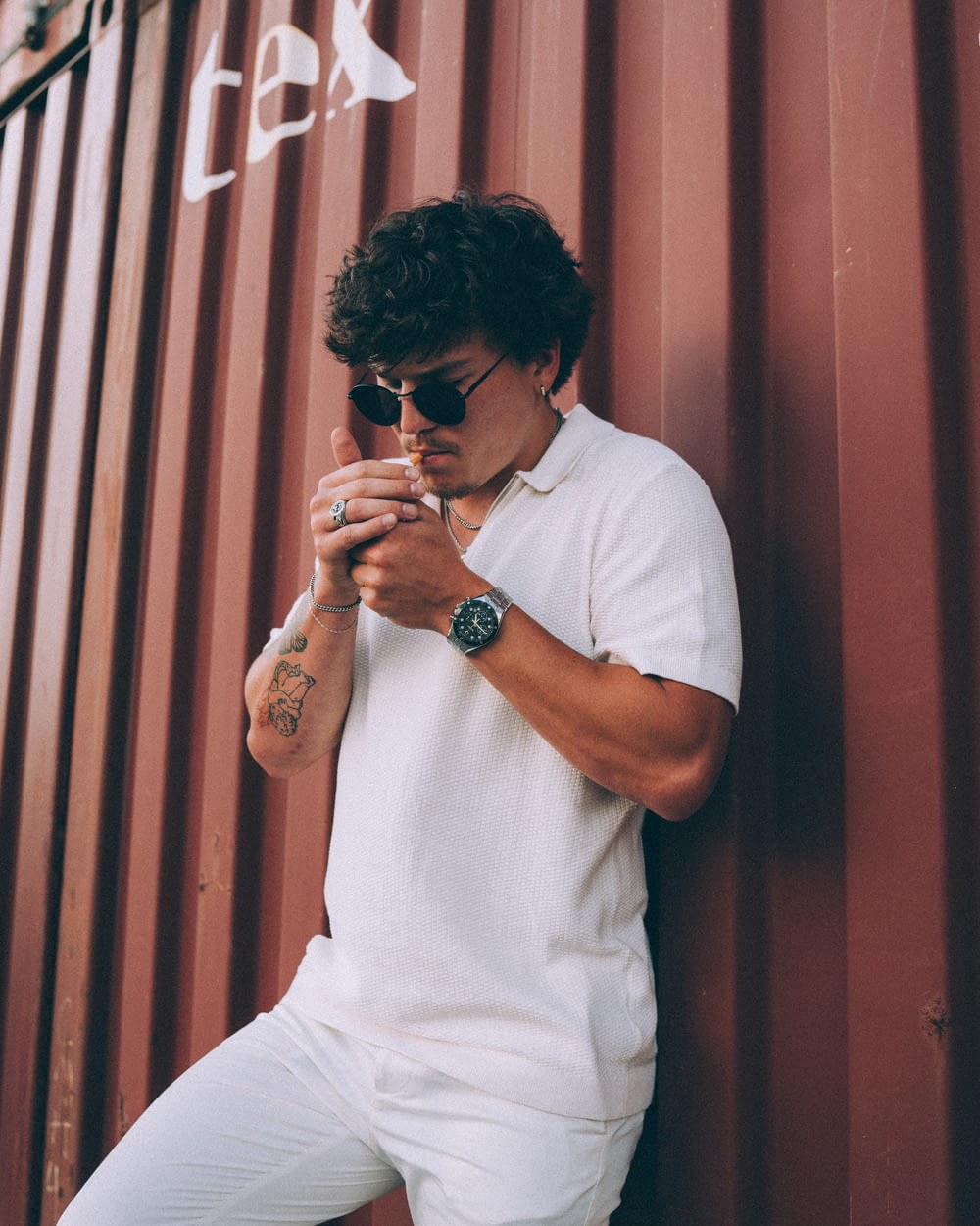 a man leaning against a wall smoking a cigarette