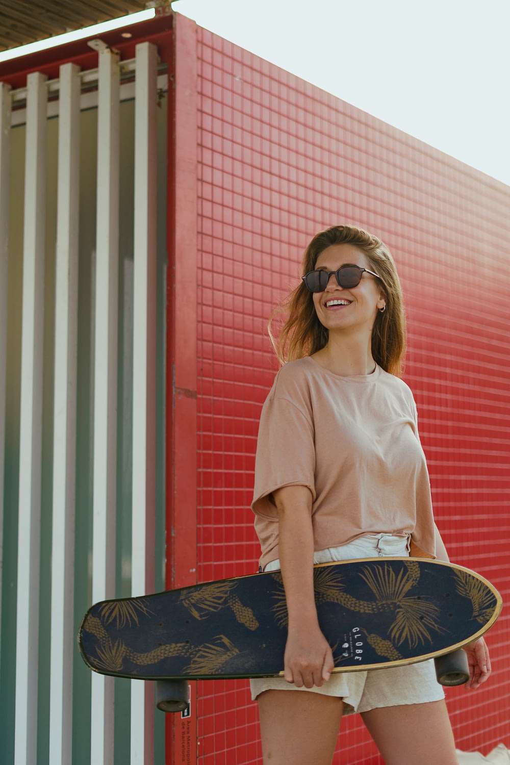 a woman holding a skateboard in front of a building
